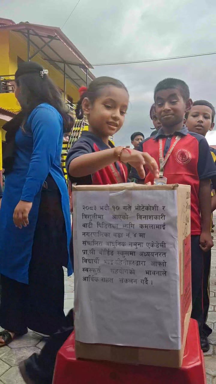 A student drops money into the flood relief collection box in the school courtyard