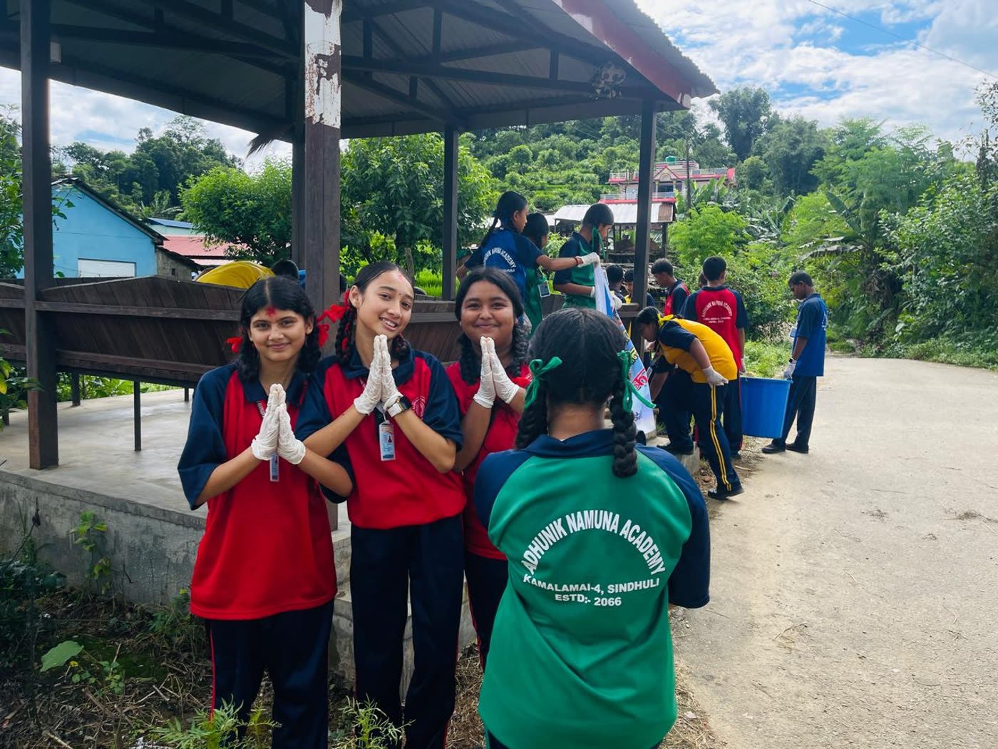 Students in gloves cleaning around the Sangwale public waiting shelter